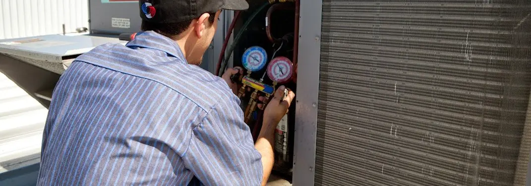 HVAC technician servicing a condenser unit in Andover